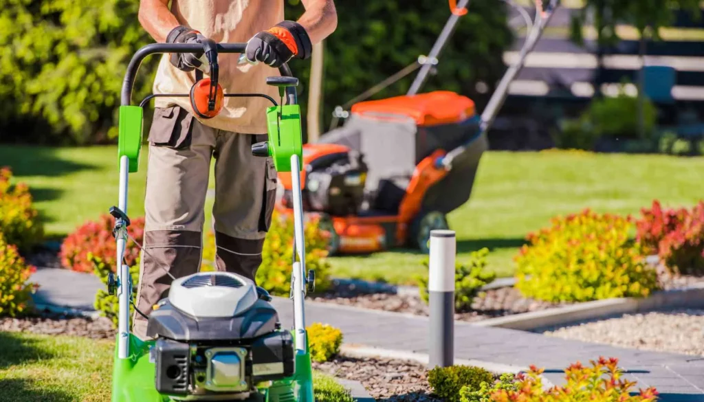 Professional landscaper performing maintenance services with a push mower and trimmer in a vibrant garden with neatly trimmed bushes and colorful flowering plants, showcasing quality landscape care in Langley.